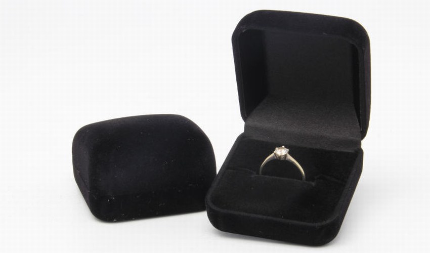 Black velvet engagement ring box with silver diamond ring.