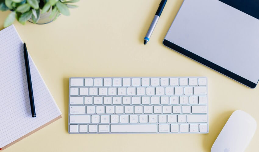 Keyboard, mouse and pen on a yellow background, implying someone is ready to make an online order.